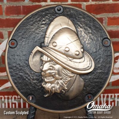 Custom cast bronze derby cover for Harley-Davidson motorcycle with Conquistador design