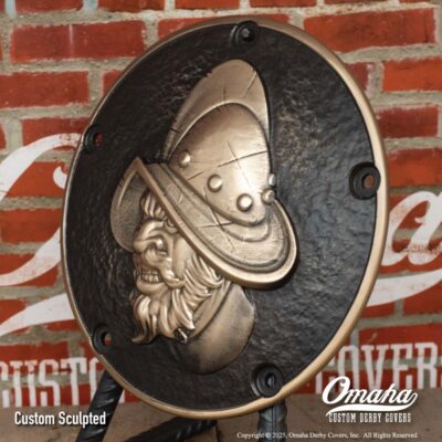 Custom cast bronze derby cover for Harley-Davidson motorcycle with Conquistador design